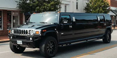 A black stretch Hummer limousine parked on a city street.