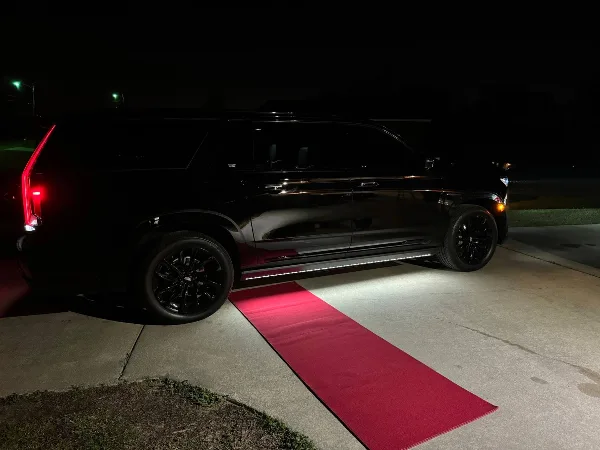 Black Cadillac Escalade SUV parked on a red carpet at night