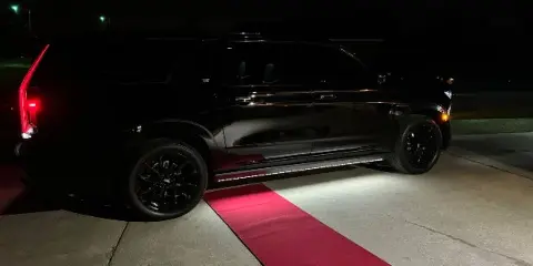 Black Cadillac Escalade SUV parked on a red carpet at night