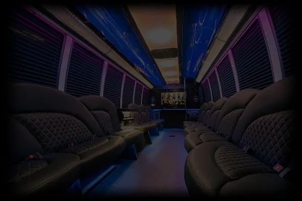 Interior view of a party bus with rows of black leather seats and purple ambient lighting.