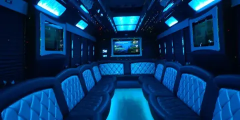 Interior view of a party bus featuring blue ambient lighting and leather bench seating.