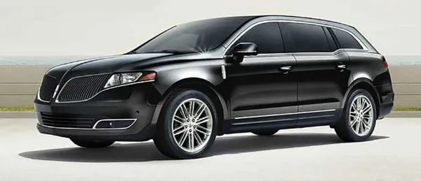 Black luxury SUV parked on a paved surface near a waterfront, representing the chauffeured transportation fleet.