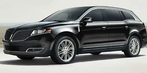 Black luxury SUV parked on a paved surface near a waterfront, representing the chauffeured transportation fleet.