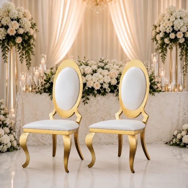 A pair of gold and white luxury wedding chairs set against a backdrop of white flowers and drapery.