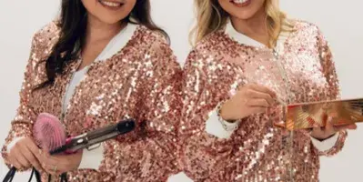 Two women in matching sequined jackets holding a hair straightener and a round brush.