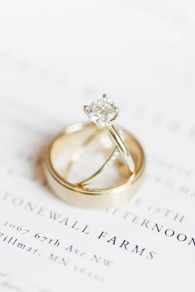 A close-up of a diamond engagement ring and wedding bands resting on a Stonewall Farms document.