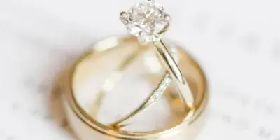 A close-up of a diamond engagement ring and wedding bands resting on a Stonewall Farms document.