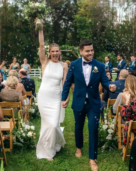 A bride and groom walking down the aisle at an outdoor wedding ceremony.
