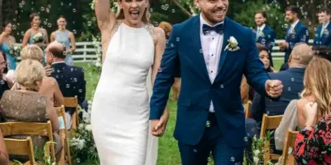 A bride and groom walking down the aisle at an outdoor wedding ceremony.