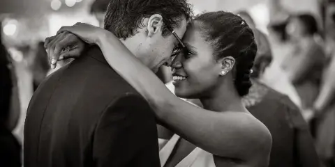 A black and white photograph of a bride and groom dancing closely together at a wedding reception.