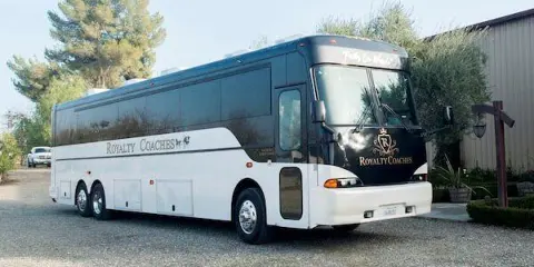 A white and black Royalty Coaches charter bus parked outdoors.