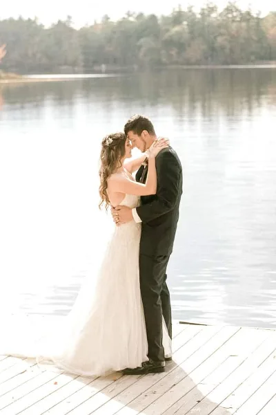 Bride and groom embracing on a wooden dock by a lake