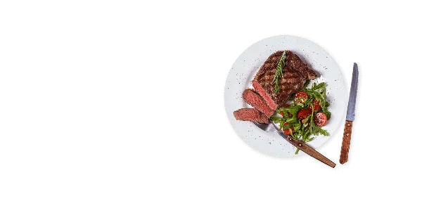 A plated steak dish with a side salad and cutlery on a black background.