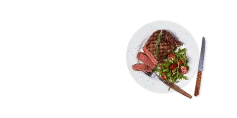 A plated steak dish with a side salad and cutlery on a black background.