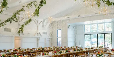 Interior of a wedding venue featuring a large floral and lighting installation on the ceiling above a banquet hall.