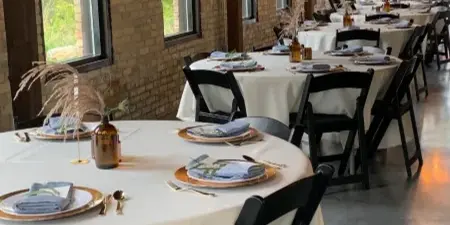 Interior view of The Mill Site event venue with set tables and brick walls.