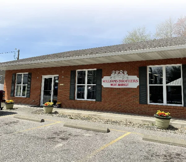 Exterior view of the Williams Brothers Meat Market brick storefront with signage and parking lot.