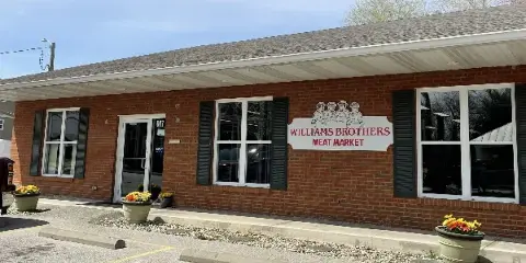 Exterior view of the Williams Brothers Meat Market brick storefront with signage and parking lot.