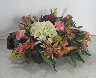 A floral centerpiece featuring white hydrangeas, pink and orange alstroemeria, and greenery.