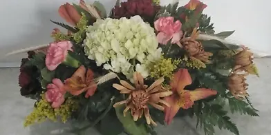 A floral centerpiece featuring white hydrangeas, pink and orange alstroemeria, and greenery.
