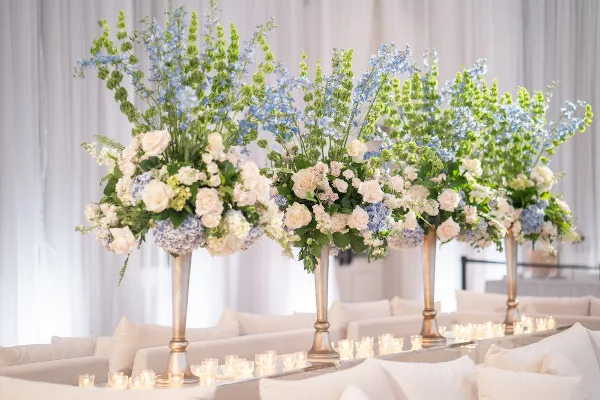 Four large floral arrangements with white roses and ornate greenery