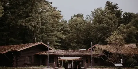 Exterior view of a historic log lodge building with a covered entrance, surrounded by tall pine trees.
