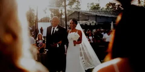 A bride and groom walking down the aisle during an outdoor wedding ceremony.