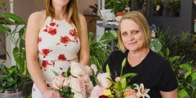 Two women holding floral bouquets in a flower shop setting