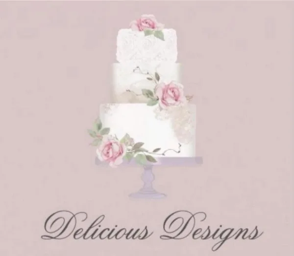 A three-tiered white wedding cake decorated with pink roses and greenery on a pedestal stand.