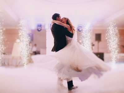 A bride and groom dancing at a wedding reception with string lights in the background.