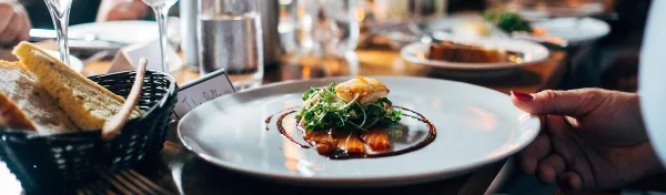 A plated food dish with garnish being served at a dining table.
