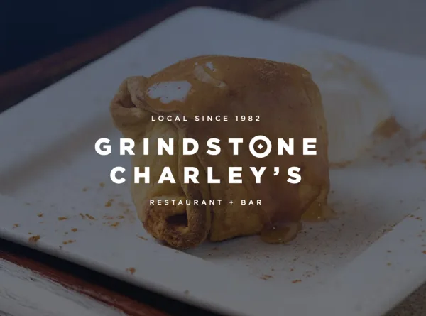 A plated food item, appearing to be a pastry or dessert, on a white square plate with the text 'Grindstone Charley's Restaurant + Bar' overlaid.