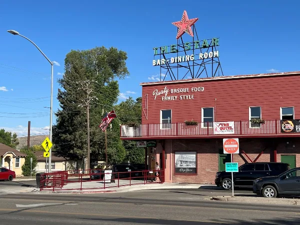 Exterior view of The Star Hotel & Bar building with a red star rooftop sign and signage advertising Basque food family style.