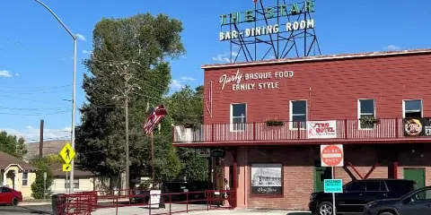 Exterior view of The Star Hotel & Bar building with a red star rooftop sign and signage advertising Basque food family style.
