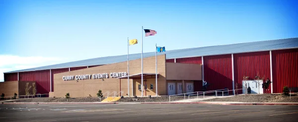 Exterior view of the Curry County Events Center building with red metal siding and a tan brick entrance.