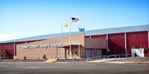 Exterior view of the Curry County Events Center building with red metal siding and a tan brick entrance.
