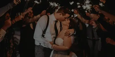 A bride and groom kissing during a sparkler send-off at a wedding reception.