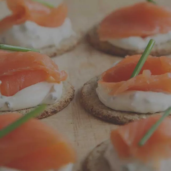 Close-up of smoked salmon appetizers on crackers with cream cheese and chives.
