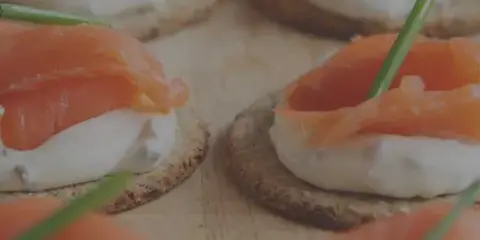 Close-up of smoked salmon appetizers on crackers with cream cheese and chives.