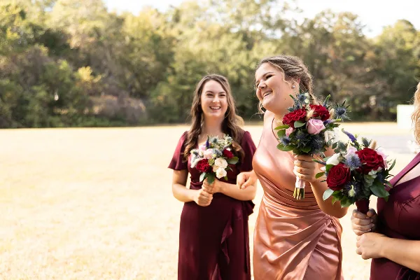 Bridesmaids in maroon dresses holding floral bouquets outdoors