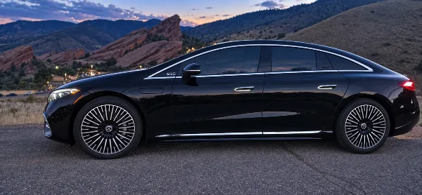 Black Mercedes-Benz EQS luxury sedan parked outdoors with Red Rocks foothills in the background.