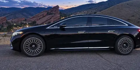 Black Mercedes-Benz EQS luxury sedan parked outdoors with Red Rocks foothills in the background.