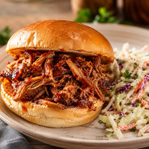 A BBQ pork sandwich served with a side of coleslaw on a plate.