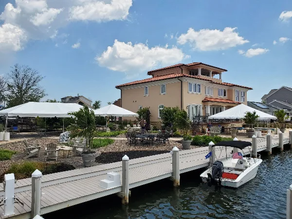 Outdoor event setup with white tents, tables, and chairs near a waterfront venue