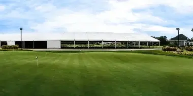 A large white event tent set up on a green lawn next to a stone building.
