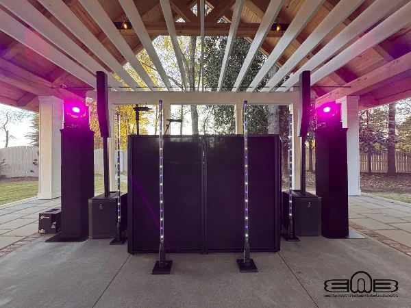 Professional DJ booth setup with speakers, lighting, and a DJ console at an outdoor venue.
