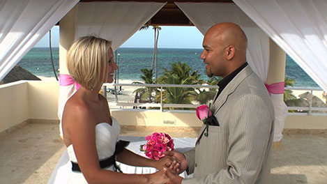 A bride and groom holding hands during a wedding ceremony at a beachside venue.