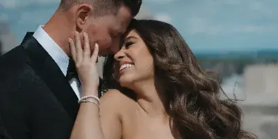 A bride and groom sharing an intimate moment outdoors, with the bride holding a bouquet of white flowers.