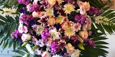 Large standing floral spray with purple, pink, and white flowers