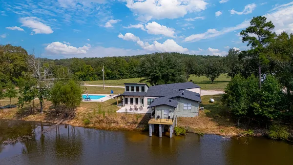 Aerial view of the Hips Hollow Farm venue featuring a large house, a swimming pool, and a pond surrounded by trees.
